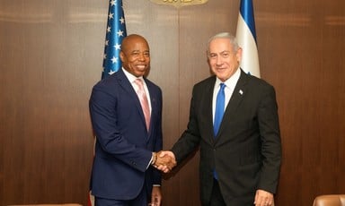 New York City Mayor Eric Adams shakes hands with Israeli Prime Minister Benjamin Netanyahu with American and Israeli flags behind them