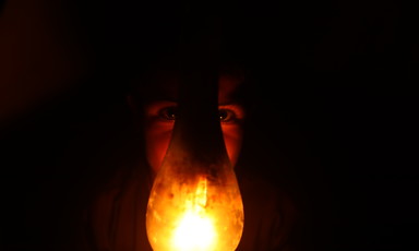 A lamp covers the face of a child amid a general scene of darkness 