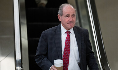 Senator Jim Risch at bottom of escalator with drink in hand