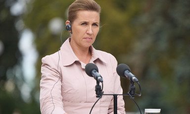 Danish PM Mette Frederiksen stands behind a microphone