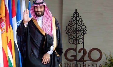 Saudi Crown Prince Mohammad bin Salman waves alongside a line of flags
