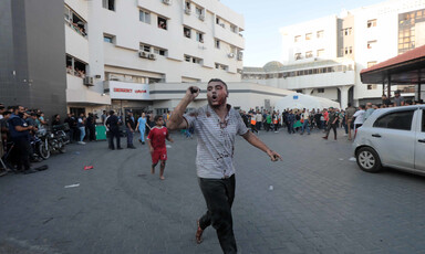 A medic who looks under severe stress points to the emergency entrance of al-Shifa hospital in Gaza City  