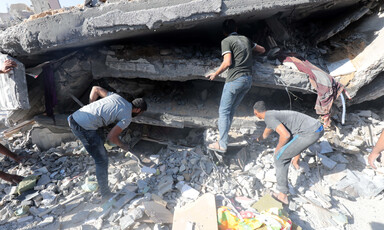 Three men search in the remains of a building that has been badly damaged by an Israeli airstrike