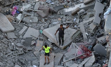 Two Palestinian children stand on rubble in al-Zahra in Gaza