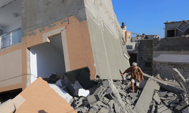 A Palestinian man walks atop rubble of a building destroyed by an Israeli airstrike