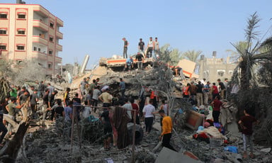 People stand on and beside what remains of a building bombed during Israel's war on Gaza 