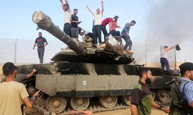 Men stand atop a smoking Israeli tank 