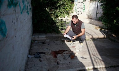 A man inspect an area splattered with blood 