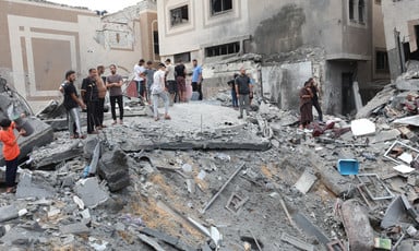 A number of men stand in what remains of a Gaza building following an Israeli airstrike 
