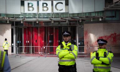 A british policeman stands guard outside the paint splattered offices of the BBC