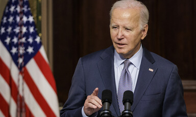 President Joe Biden stands at presidential podium with a US flag next to him