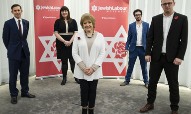 Five people standing in front of Jewish Labour Movement banners