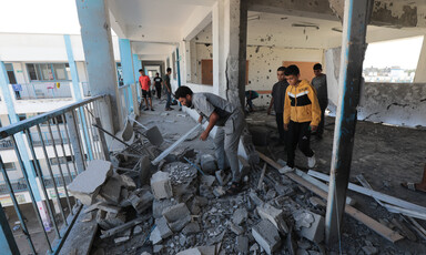 Men and children sift through rubble on the third floor of a damaged building