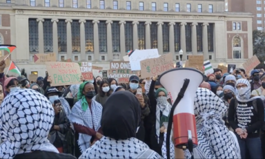 Students wearing traditional Palestinian scarves and holding signs and bullhorns protest on Columbia University's campus