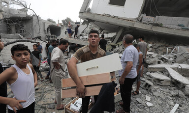 A group of boys and young men searches in what remains of a home bombed by Israel 