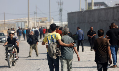 A view of the backs of two men walking, arms around each others' backs