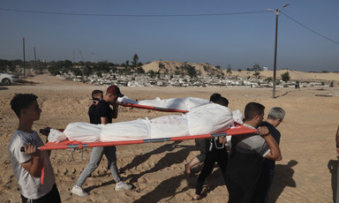 A group of men carry two dead bodies wrapped in shrouds on stretchers following an Israeli airstrike in Gaza 