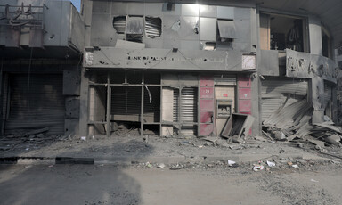 The destroyed and dust-covered facade of al-Watan Tower in Gaza with broken windows. 