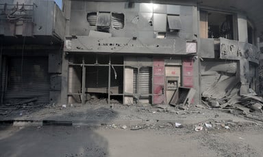The destroyed and dust-covered facade of al-Watan Tower in Gaza with broken windows. 