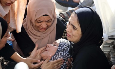 Three Palestinian women and a child comforting a woman