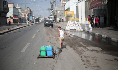 A boy pulls containers on a street in the city of Rafah in the Gaza Strip