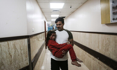 A man carries his injured daughter through a hospital corridor