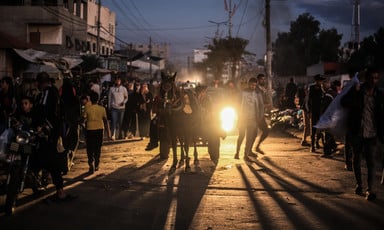 A horse and cart are backlit by car headlights in a street in Gaza