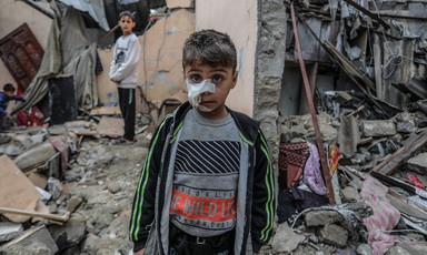A boy with a dressing on his face stands in what remains of a building in Gaza 