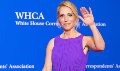 Dana Bash waves in front of a blue background with white lettering saying White House Correspondents' Association and WHCA
