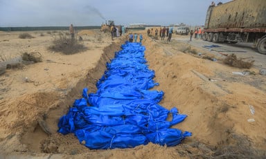 A row of blue bags containing corpses in a shallow grave