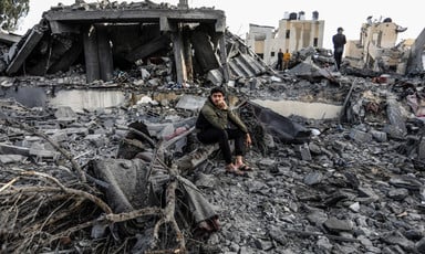 A man sits in what remains of a home following an Israeli attack 