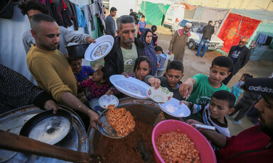 Children and a few adults queue for food in Gaza 
