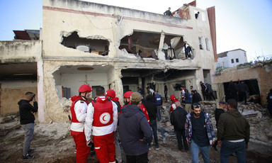 People and uniformed civic workers check the damage to a shelled house 