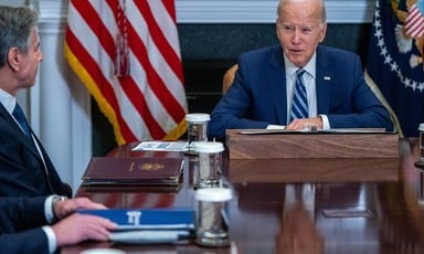 Joe Biden and Antony Blinken seated with an American flag between them