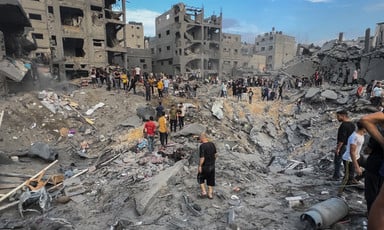 People walk in and search through the rubble of Jabaliya refugee camp after it was attacked by Israel 
