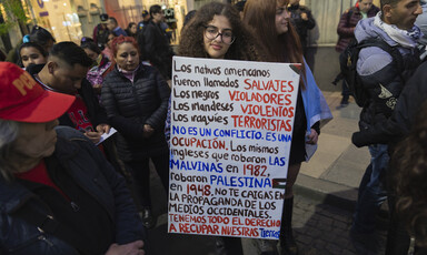 A woman holds a sign with writing in Spanish