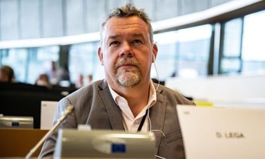 Member of the European Parliament David Lega sits at a desk wearing earphones 