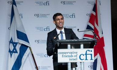 British Prime Minister Rishi Sunak stands at a podium with the flags of Britain and Israel behind him