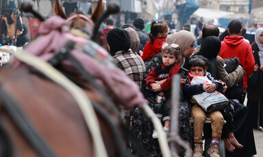 A busy street with children and horse drawn carriages