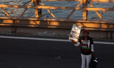 A woman stands alone with a placard