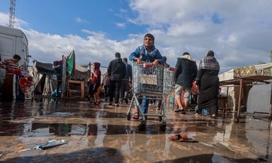 A boy pushes a shopping cart in a puddle of rainwater