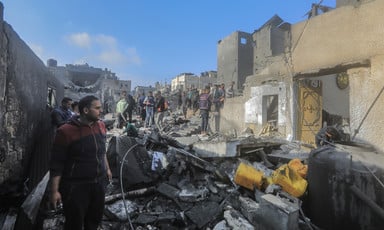 People stand in what remains of buildings following an Israeli airstrike 