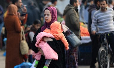 A woman carries a child after fleeing her home in Gaza 