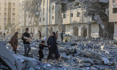 A number of people walk in the rubble of Gaza's Hamad City after it was attacked by Israel 