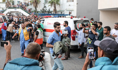 A medic carries an injured child beside an ambulance in the grounds of al-Shifa hospital, Gaza City