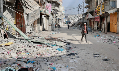 Some people walk amid destroyed and badly damaged buildings in the southern Gaza city of Khan Younis 