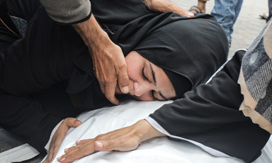 A woman places her head on a corpse covered in a white sheet