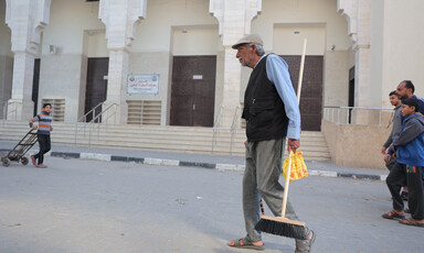 A man carries a broom down a street