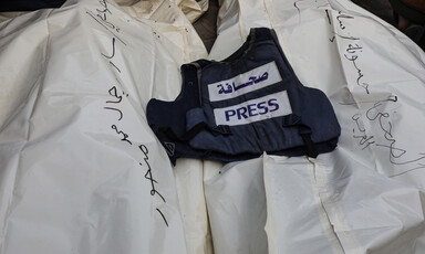 A press vest is laid atop two body bags 