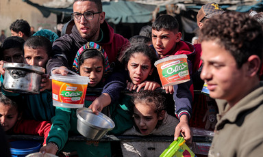 Children and some adults hold empty containers as the queue for food aid in Gaza